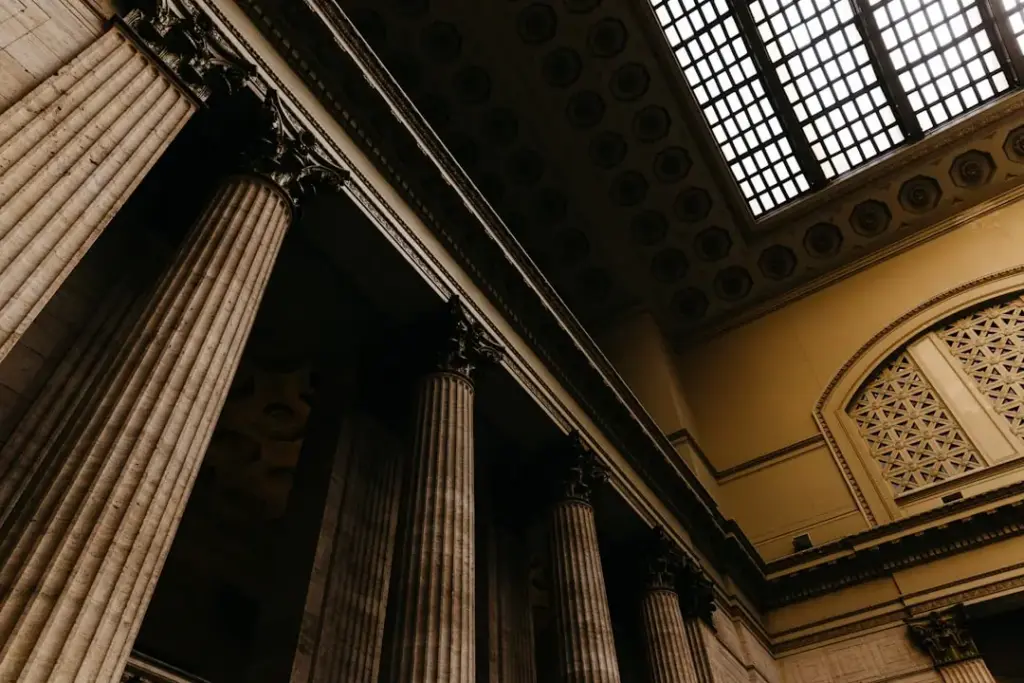 Low-angle view of fluted Corinthian columns and a coffered ceiling with skylight inside a classical courthouse building
