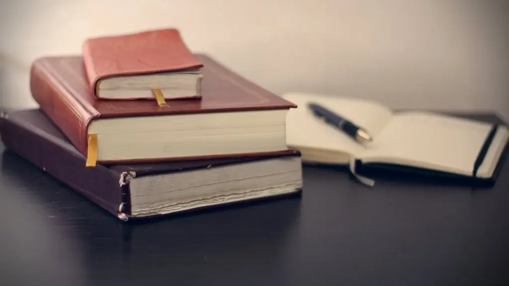 Stack of three hardcover law books beside an open notebook with a pen on a dark desk.